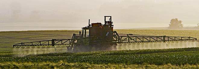 Farming equipment spraying Monsanto Roundup in a field. 